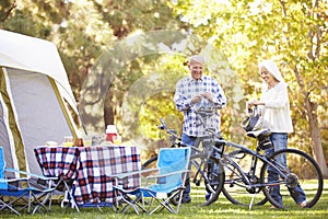 Senior Couple Riding Bikes On Camping Holiday