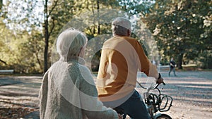 Senior couple riding double bicycle in autumn. Cycling together . Elderly people healthy and active lifestyle.