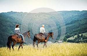 A senior couple riding horses in nature.