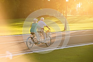 Senior couple riding tandem bicycle.