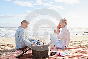 Senior couple, romantic beach picnic and smile together in summer for conversation, memory and comic time. Elderly man