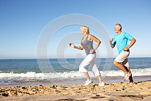 Senior Couple Running Along Beach