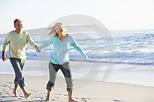 Senior Couple Running Along Beach