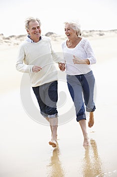 Senior Couple Running Along Beach Together