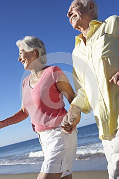 Senior Couple Running Along Beach Together