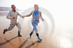 Senior Couple Running Along Winter Beach