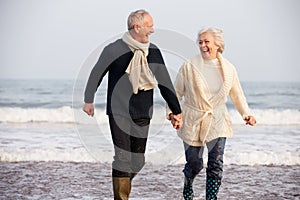 Senior Couple Running Along Winter Beach