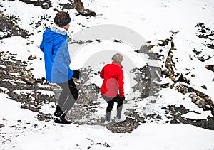 A senior couple running downhill in snowy winter nature.