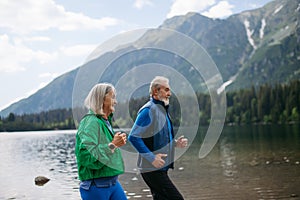 Senior couple running by the lake in the mountains.