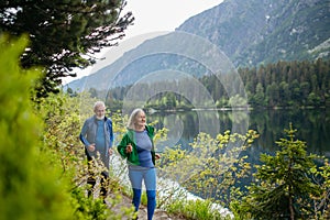 Starší pár běží u jezera v horách.