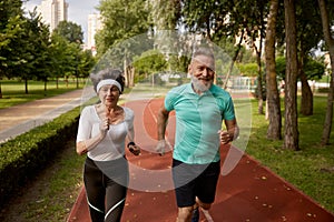 Senior couple running on track together at natural park