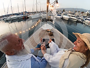 Senior couple on sailboat vacation - Happy elderly people having fun celebrating wedding anniversary on boat trip