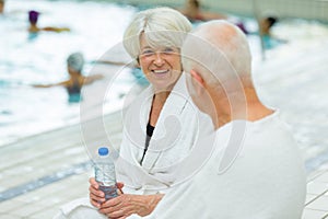 senior couple sat talking poolside