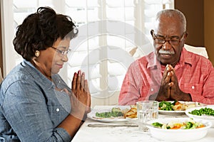 Senior Couple Saying Grace Before Meal At Home