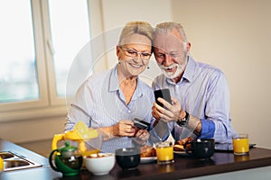 Senior couple shopping online with phone and credit card