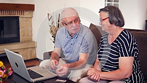 Senior couple shopping online using credit card on laptop