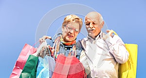 Senior couple shopping together with wife watching in husband bags - Elderly concept with mature man and woman having fun