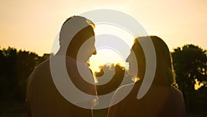 Senior couple silhouette embracing, watching sunset together, romantic date