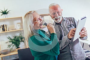 Senior couple singing karaoke at home photo
