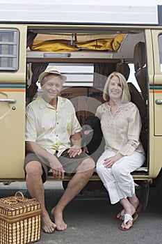 Senior Couple Sit In Campervan With Their Pet Dog