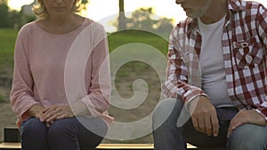 Senior couple sitting apart on bench outdoors, deception, breakup and resentment