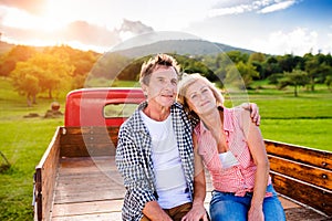 Senior couple sitting in back of red pickup truck