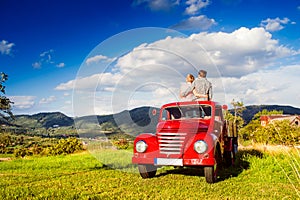 Senior couple sitting in back of red pickup truck