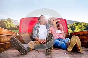 Senior couple sitting in back of red pickup truck