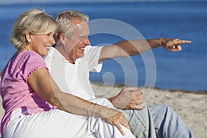 Senior Couple Sitting on Beach Pointing