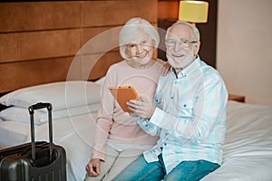 Senior couple sitting on a bed and watching something on a talet