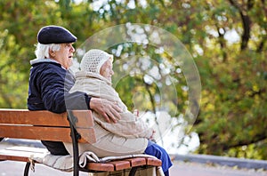 Senior couple sitting on bench in autumn park