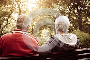 Senior couple sitting on bench after exercise. From back.