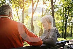 Senior couple sitting on bench after exercising and having conversation.