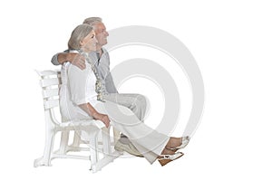 Senior couple sitting on bench isolated on white background, full length