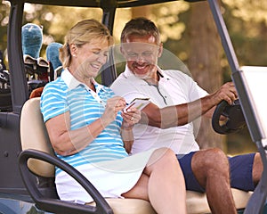 Senior Couple Sitting In Buggy On Golf Course Marking Score Card Together