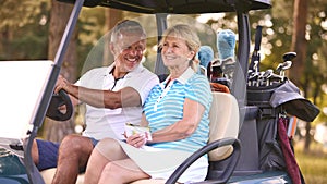 Senior Couple Sitting In Buggy On Golf Course Marking Score Card Together