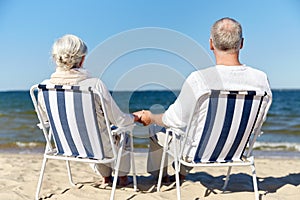 Senior couple sitting on chairs at summer beach