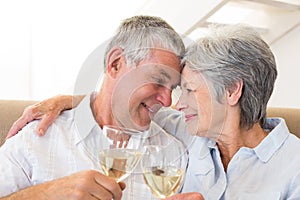 Senior couple sitting on couch having white wine