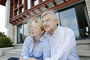 Senior couple sitting in front of beautiful home