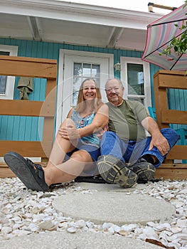 Senior couple sitting in front of house