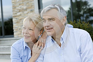 Senior couple sitting in front of house