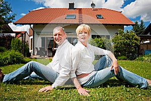 Senior couple sitting in front of their home