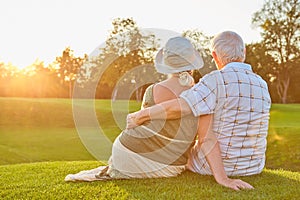 Senior couple sitting on grass.
