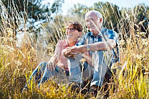 Senior couple sitting in the grass enjoying themselves