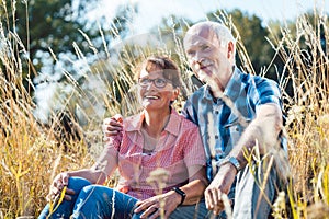 Senior couple sitting in the grass enjoying themselves