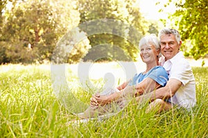 Senior couple sitting on grass together relaxing