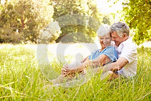 Senior couple sitting on grass together relaxing