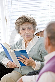 Senior couple sitting on living room couch reading
