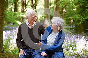 Senior Couple Sitting On Log In Bluebell Wood