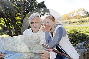 Senior couple sitting by river looking at map